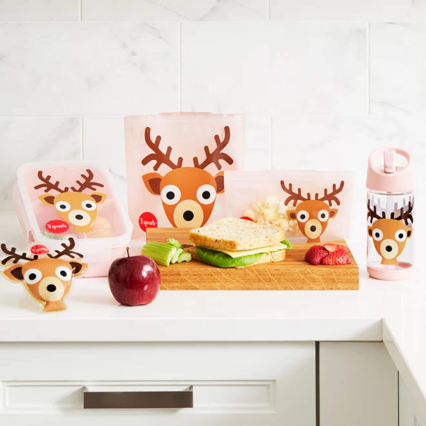 3 Sprouts Deer lunch range on a kitchen counter, featuring the sandwich bag, snack bag, bottle, and lunchbox with food.