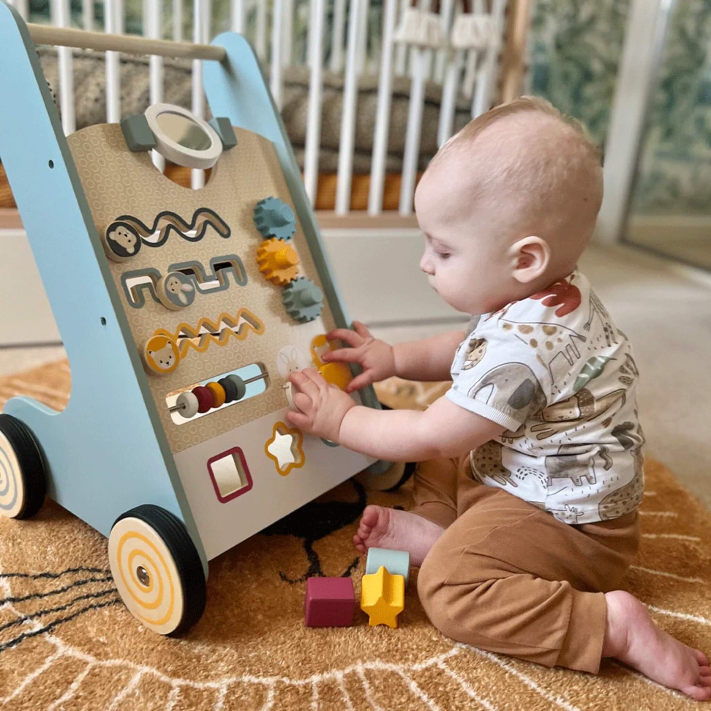 Baby exploring the activity walker, practising fine motor skills with sliding blocks and spinning gears.