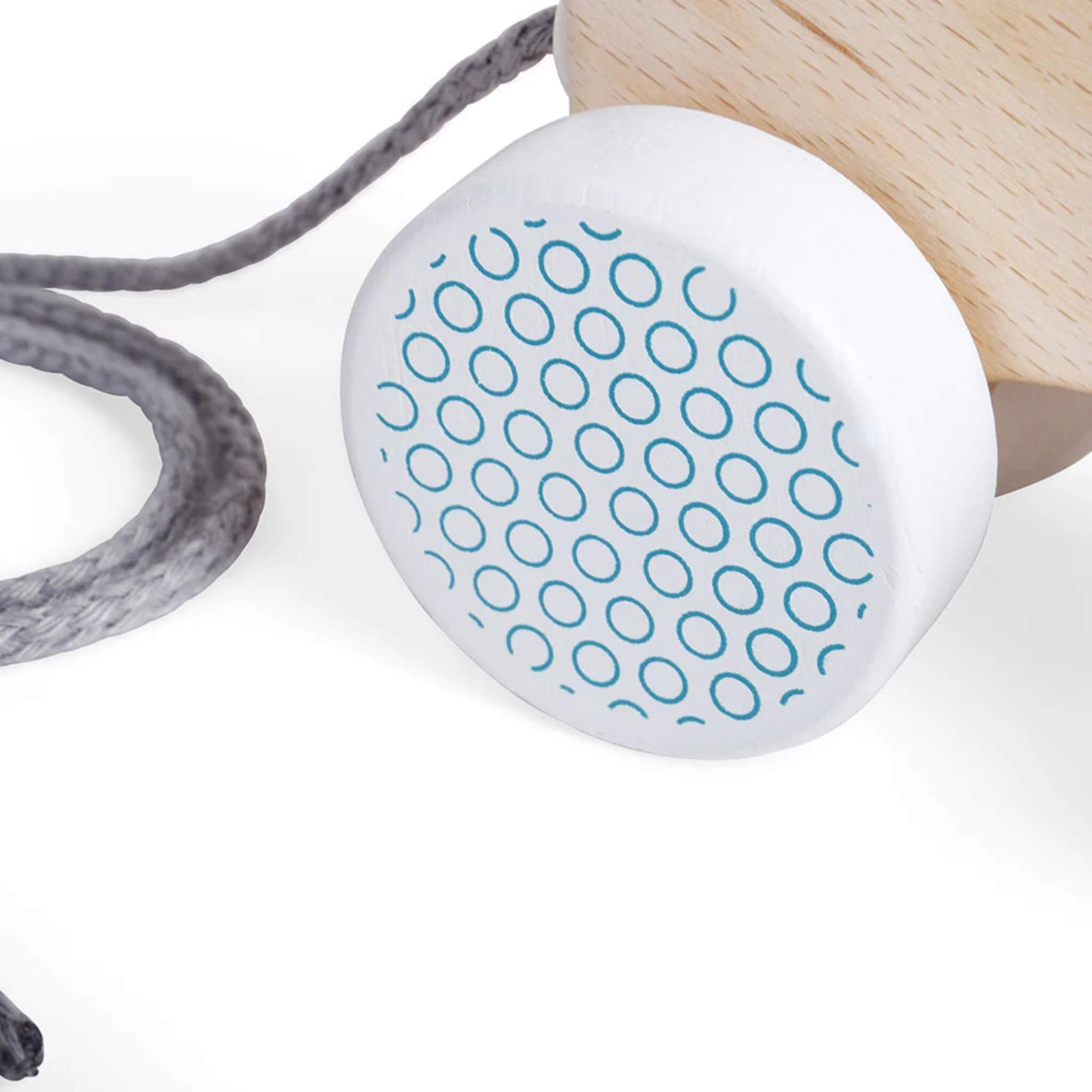 Detail of one patterned wheel on the Bigjigs pull along bear, showing the light blue circular design and the attached grey cord.