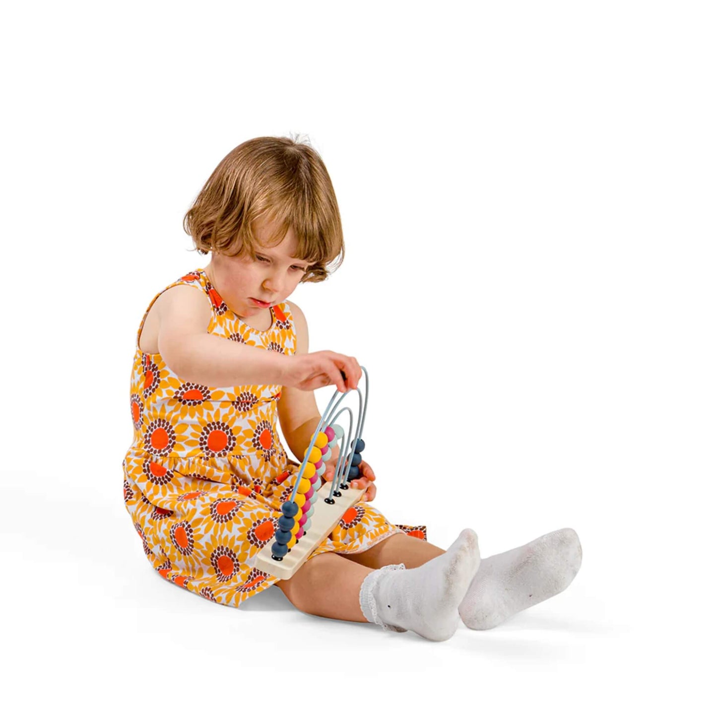 Young child holds the abacus upright while seated, exploring the silicone beads with curiosity.