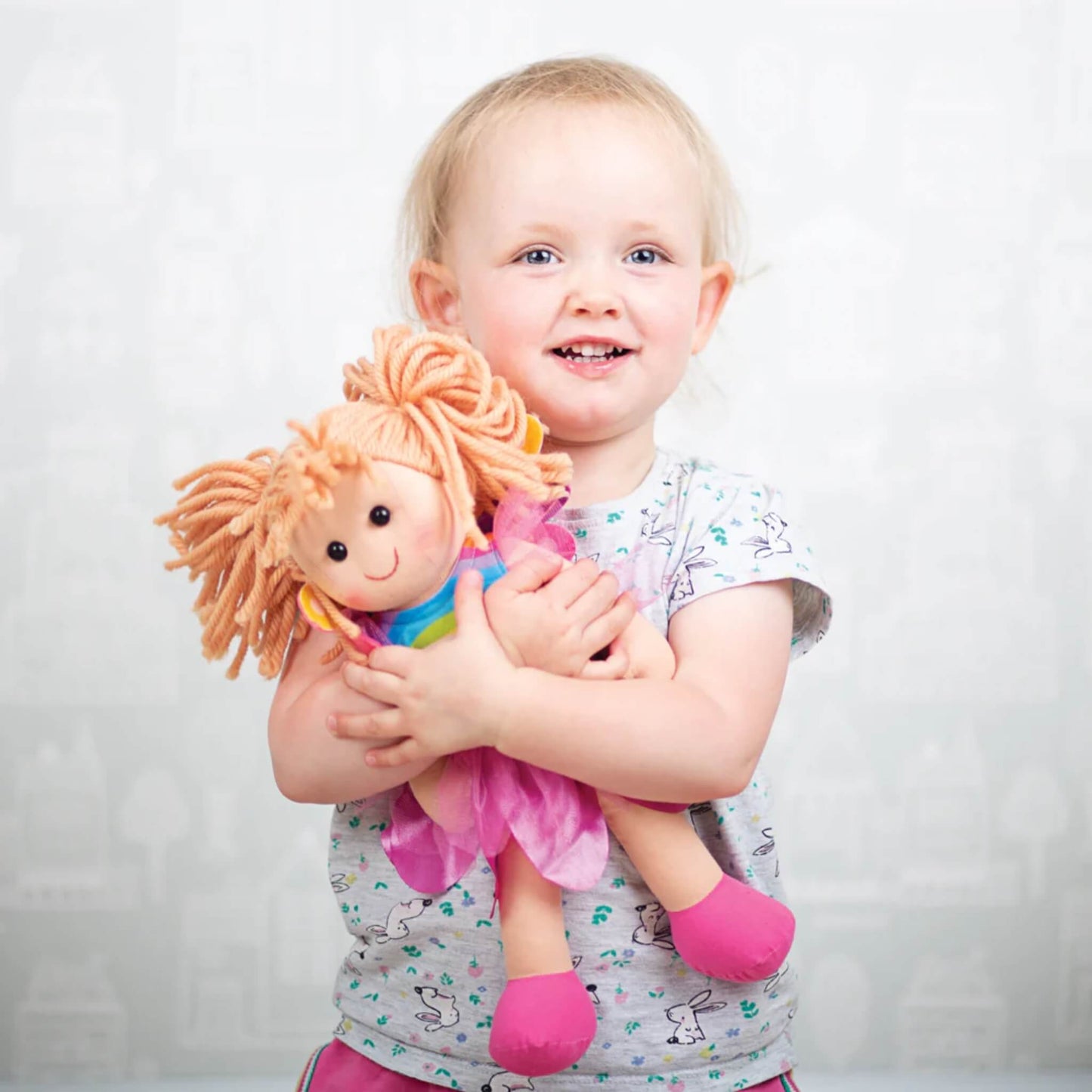 Toddler cuddling Chloe Doll close to her chest, showing the doll's bright colours and soft, friendly features.