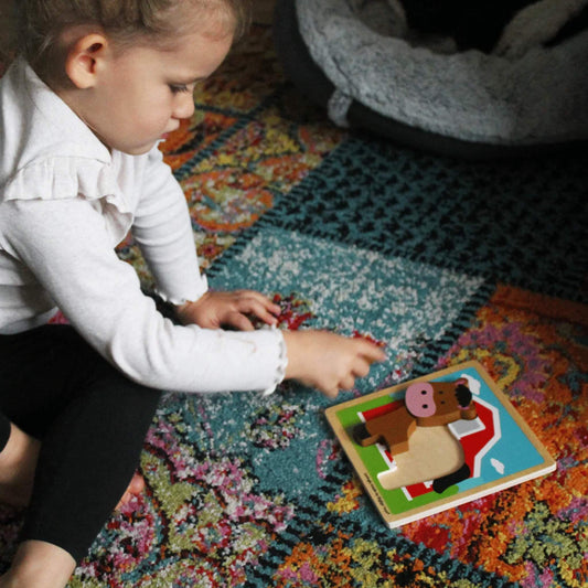 A toddler carefully placing chunky horse puzzle pieces on a sturdy wooden base, exploring shapes and colours.