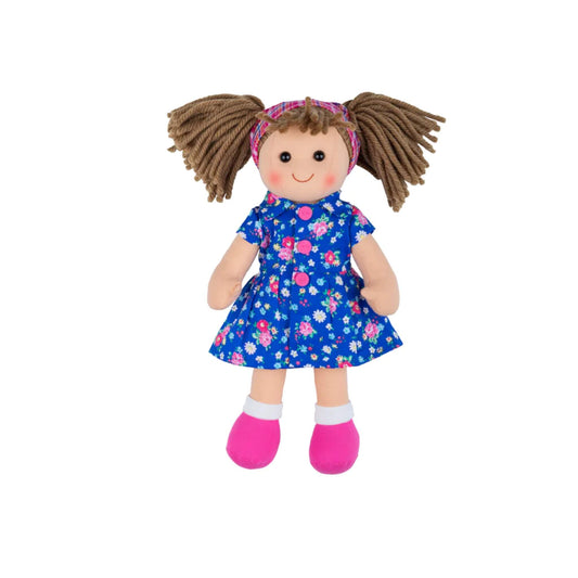 Front-facing view of the Hollie doll standing upright, showing her blue floral dress, bright pink shoes, and brown yarn pigtails tied with a checked headband.