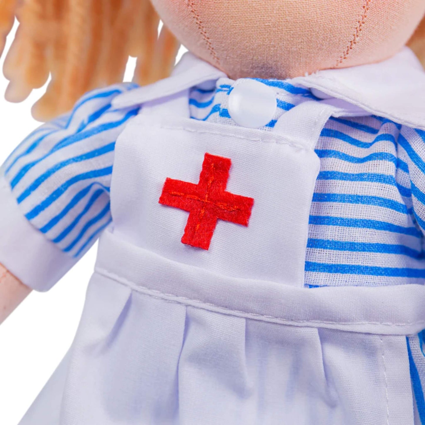 Detail of the stitched red cross on the doll’s apron, with striped blue sleeves visible on either side.