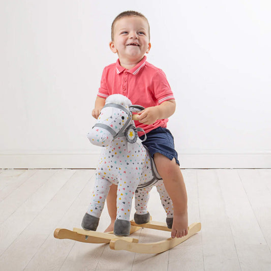 Toddler smiling while riding the Bigjigs Patterned Rocking Horse, showcasing its ideal size and sturdy handles.