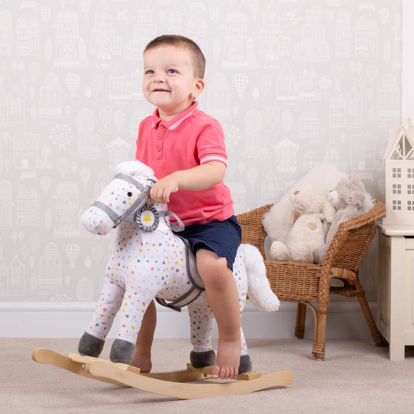Child enjoying playtime on the Bigjigs Rocking Horse, surrounded by toys in a bright nursery room.
