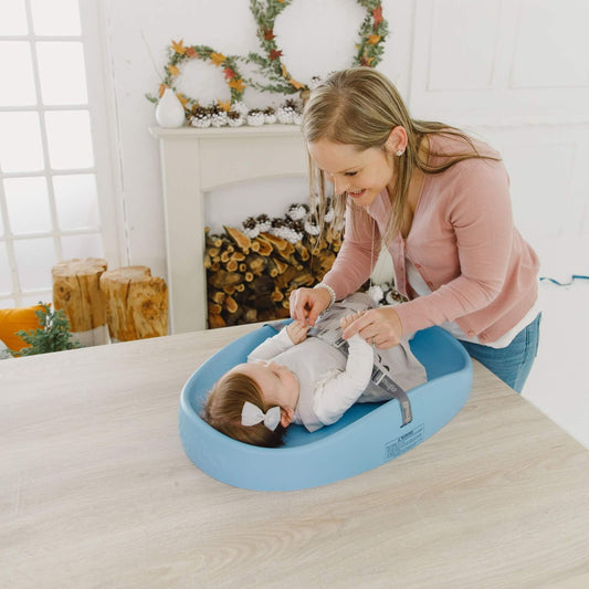 Mother engaging with baby while lying on Bumbo Powder Blue Changing Pad.