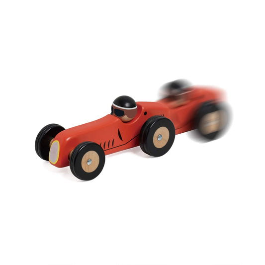 Red wooden Monaco toy race car captured in motion, with a blur effect showing the toy speeding across a surface.