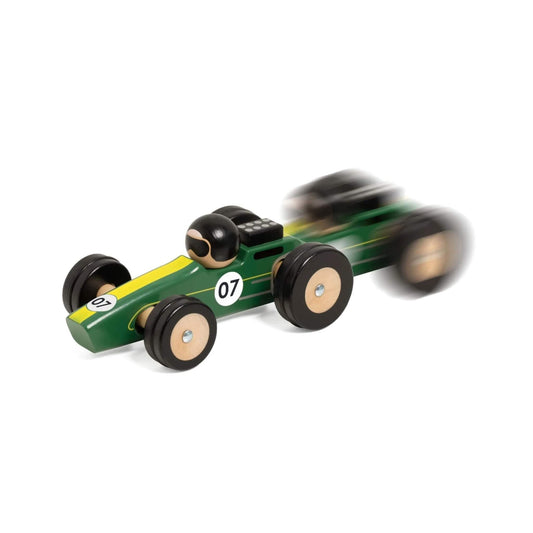 Green wooden Silverstone toy race car captured in motion, with a blur effect showing the toy speeding across a surface.