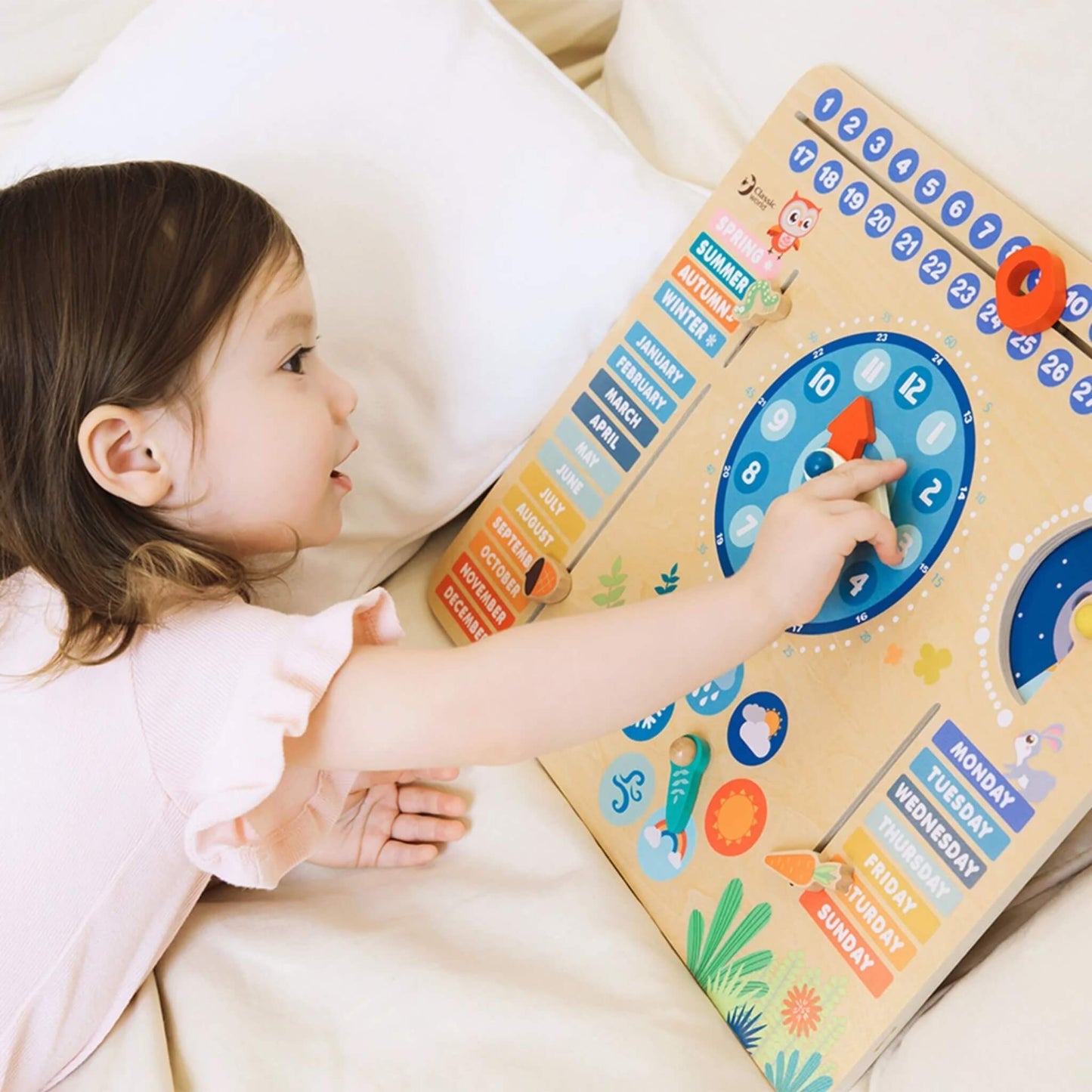 Child adjusting clock hands on a wooden learning calendar board with movable weather pieces, colourful months, seasons and days of the week.