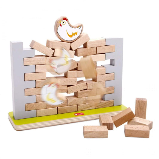 Wooden blocks tumbling from a collapsing wall as part of a children’s balancing game, with a painted chicken figure falling mid-air and bricks scattered below.