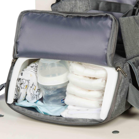 A close-up of an open storage compartment filled with nappies, a baby bottle, wipes, and muslins.