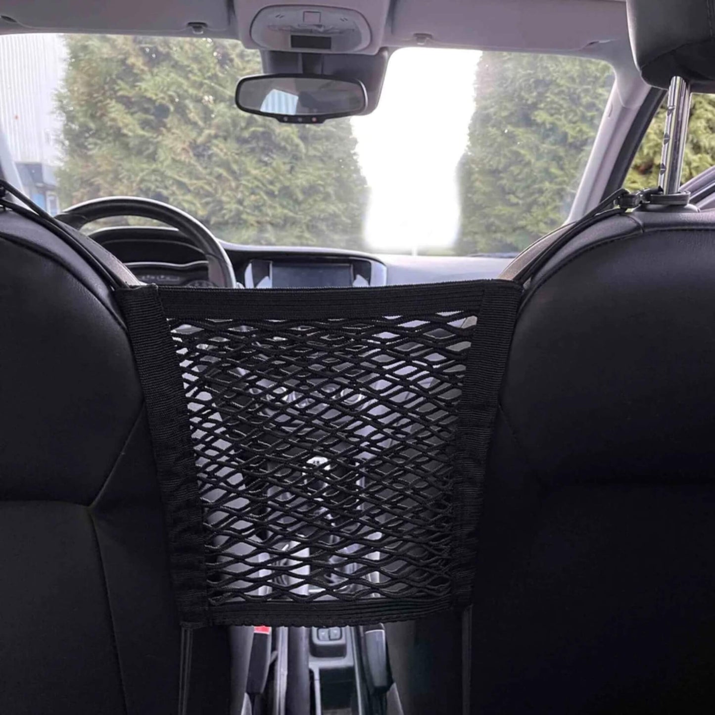 A black mesh car seat organiser installed between two black front car seats, viewed from the back seat looking towards the dashboard.
