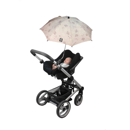 A baby lying in a rear-facing stroller seat under an open parasol with a beige canopy and leaf-patterned print.