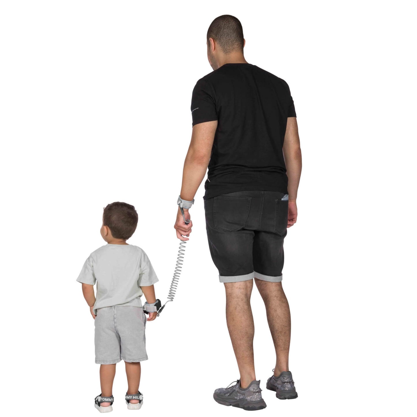 An adult and child walking away, both wearing padded safety wristbands connected by a coiled tether.