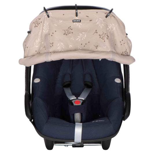 A beige leaf-print sunshade attached to a navy blue infant car seat, partially rolled up to reveal the harness area.