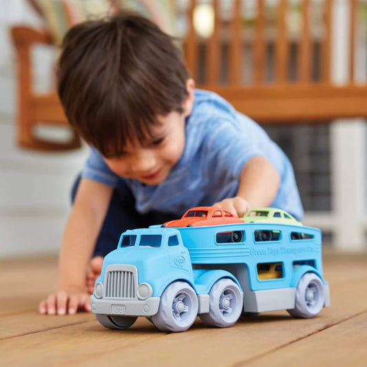 Young child playing on the floor, pushing the loaded car carrier truck with Mini Cars stacked on top.