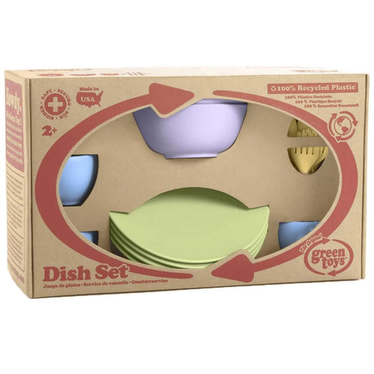 Packaging of the Green Toys Cookware & Dining Set showing plates, bowls, cups, and utensils through a cutout window on the recycled cardboard box.