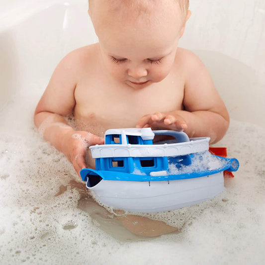 Toddler sitting in a bubble bath, gently playing with the Paddle Boat, which is floating on the surface.