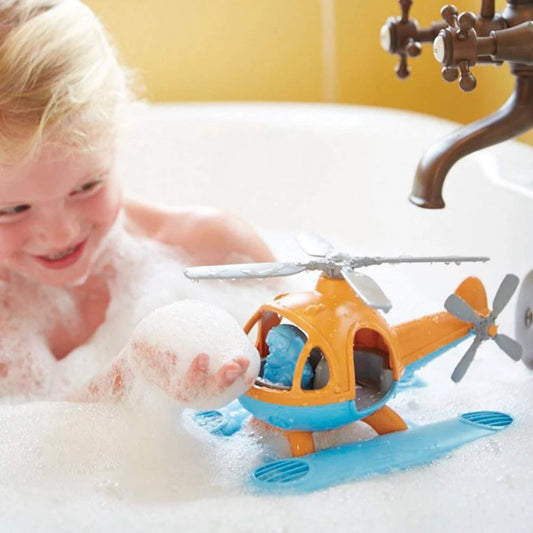 Child playing in a bubble bath, smiling at the Seacopter floating on the water with the blue bear pilot inside the cockpit.