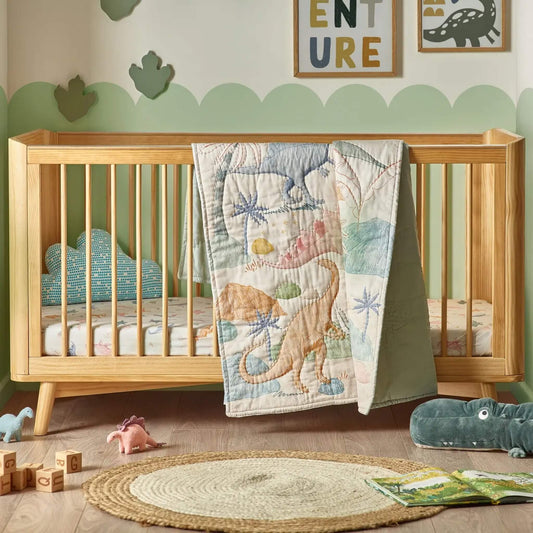 A wooden cot bed with a dinosaur-patterned quilt draped over the rail, showing large illustrated dinosaurs in muted greens, blues, and warm neutrals.