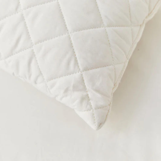 Close-up of a quilted pillow corner showing diamond stitching, soft cotton fabric and gentle padding detail.