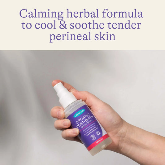 Hand holding a bottle of post-birth relief spray against a soft neutral background, highlighting a cooling herbal formula designed to soothe tender postpartum skin.