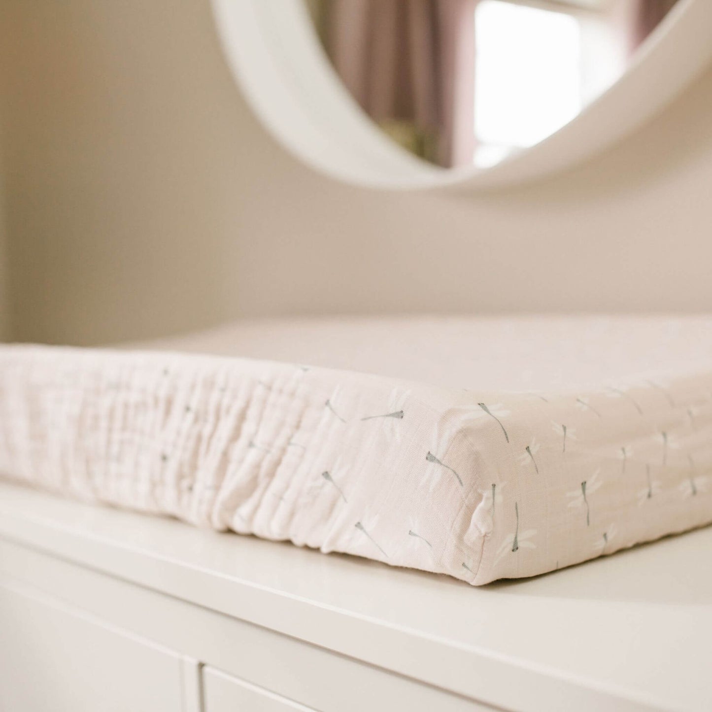 Lulujo dragonfly patterned changing pad cover installed on white dresser in a baby nursery setting, showcasing the soft cream fabric.