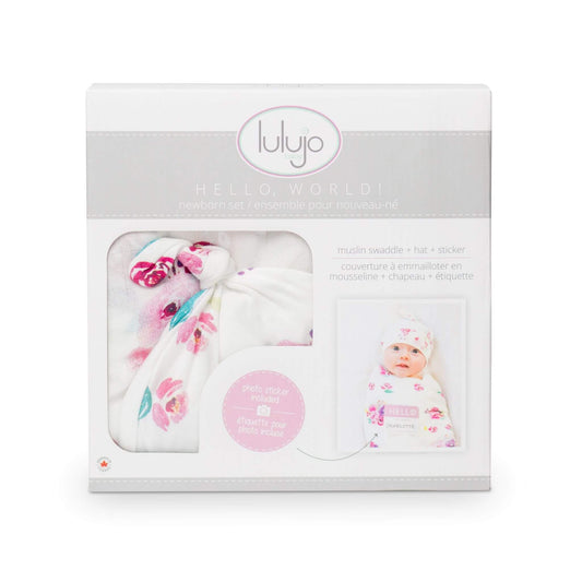 Lulujo Hello World newborn set packaging with muslin swaddle, knotted hat and name sticker in white with pink floral watercolour design.