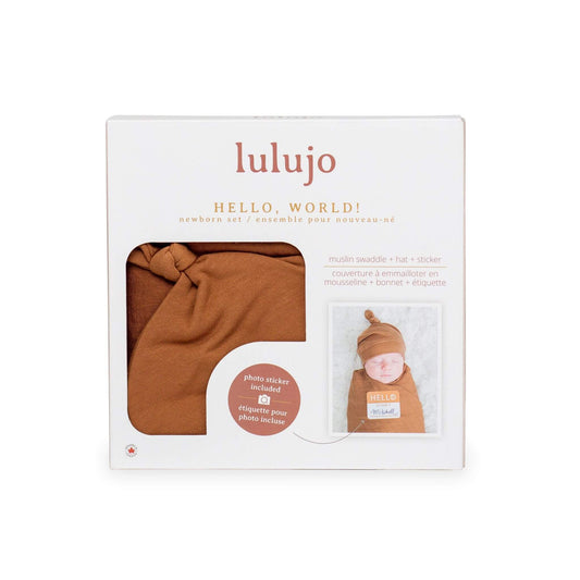 Lulujo Tan Hello World gift box showcasing muslin swaddle, knotted hat and photo sticker with baby Mitchell featured in sample photo.