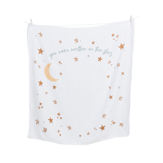 Lulujo white muslin blanket with 'You were written in the stars' quote, golden crescent moon and stars pattern hanging on clothesline, perfect for monthly baby photos.