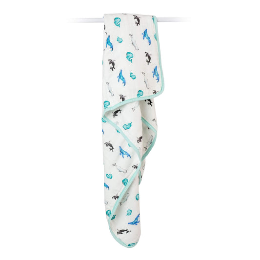 Lulujo Quilted Blanket in Whale print draped over a rail, displaying its lightweight fabric and charming sea creature design.