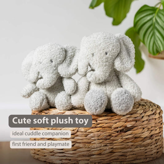 A pair of soft plush elephant toys sitting on a woven basket, both facing forward with rounded limbs and textured fur. The words “Cute soft plush toy”, “ideal cuddle companion” and “first friend and playmate” appear on the image.