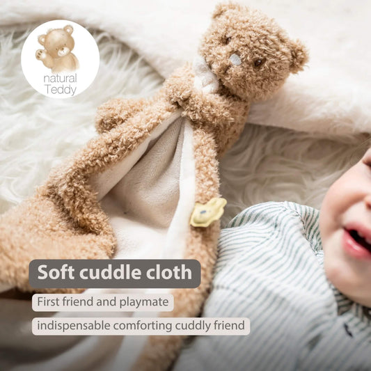 Baby holding a soft beige security blanket with an attached plush bear, shown with the text ‘Soft cuddle cloth’, ‘First friend and playmate’ and ‘indispensable comforting cuddly friend’ on the image.