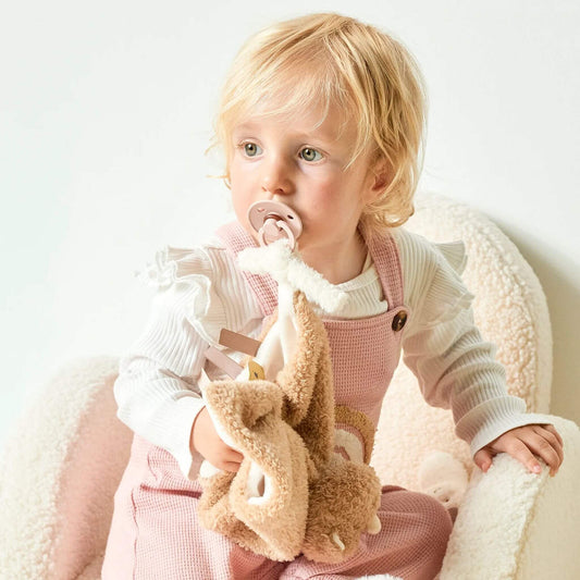 Toddler with a rhino doudou comfort blanket, demonstrating its soothing design and pacifier attachment feature.
