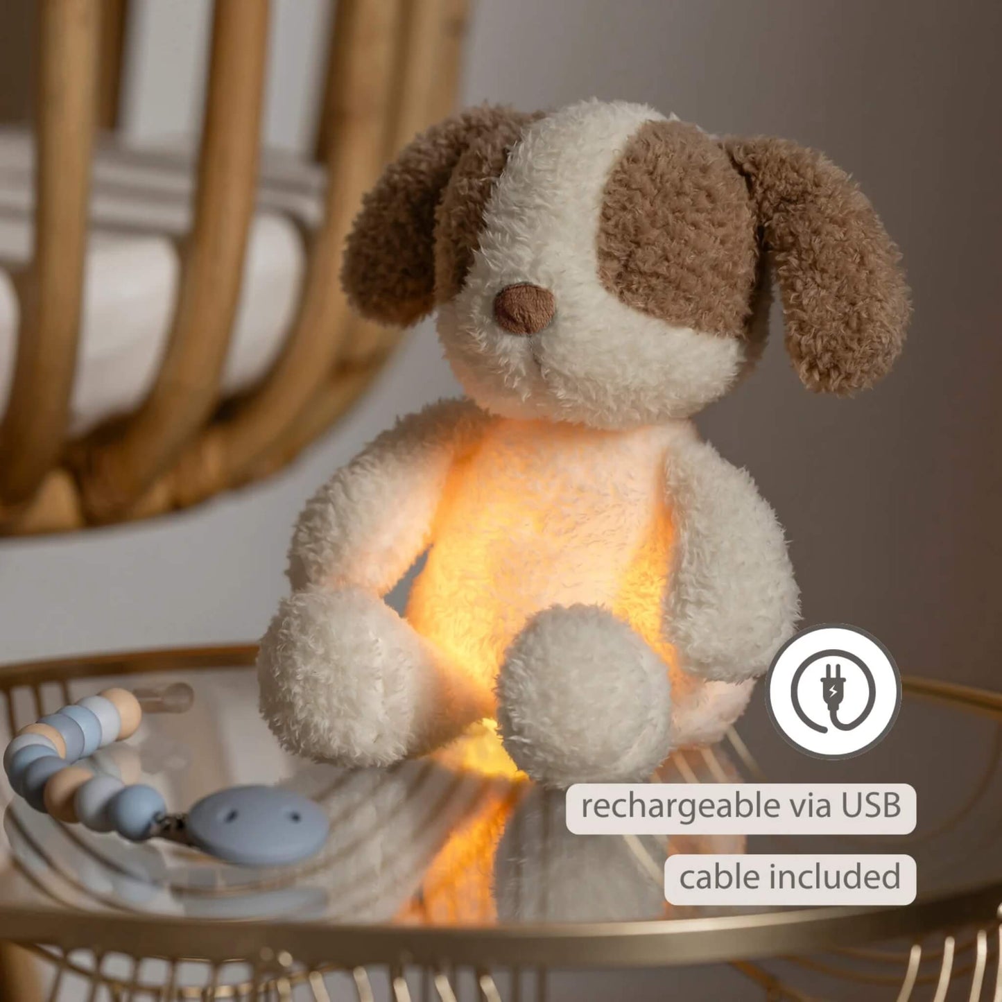 A glowing plush dog nightlight resting on a bedside table with a USB charging icon beside it.