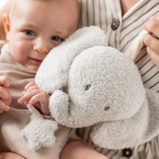 Baby cuddling a plush teddy musical elephant, enjoying its soft fabric and soothing music.