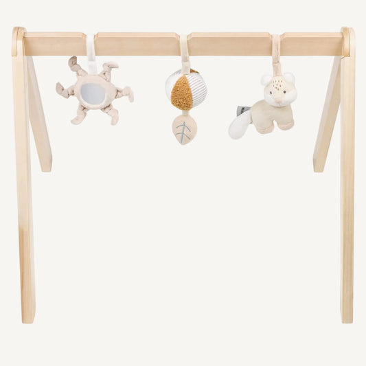 Wooden baby play arch with three soft hanging sensory toys including a mirror sun, textured ball and plush animal, shown against a plain background.