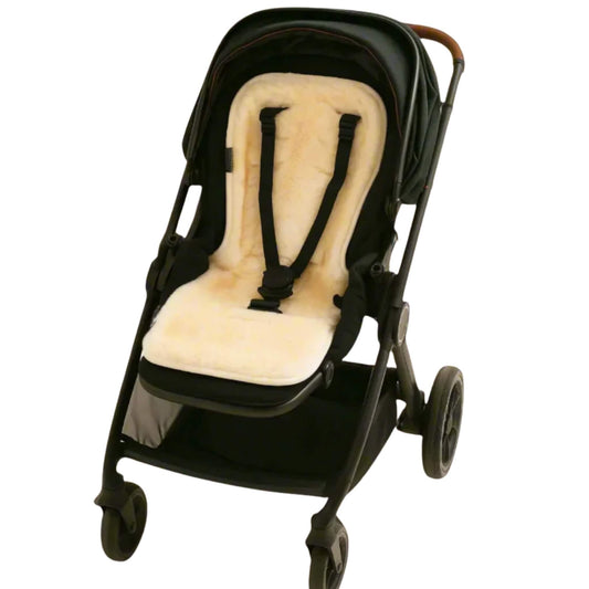 Baby sheepskin pram liner fitted neatly inside a black pushchair with harness straps threaded through.
