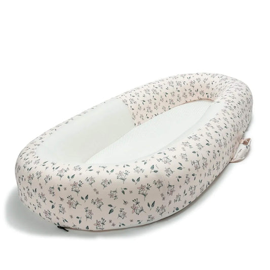 A top-down view of a baby bed with floral patterned sides and a breathable mesh base.