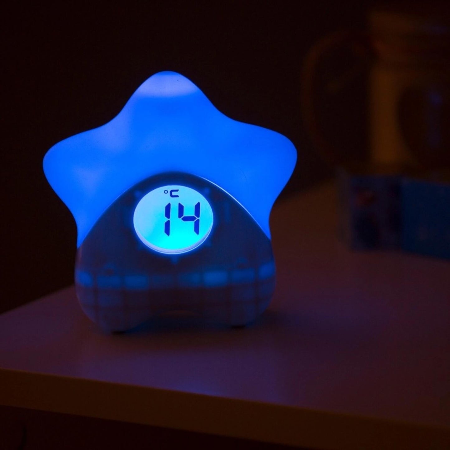 Star-shaped room thermometer glowing blue with digital temperature display reading 14°C in low light.