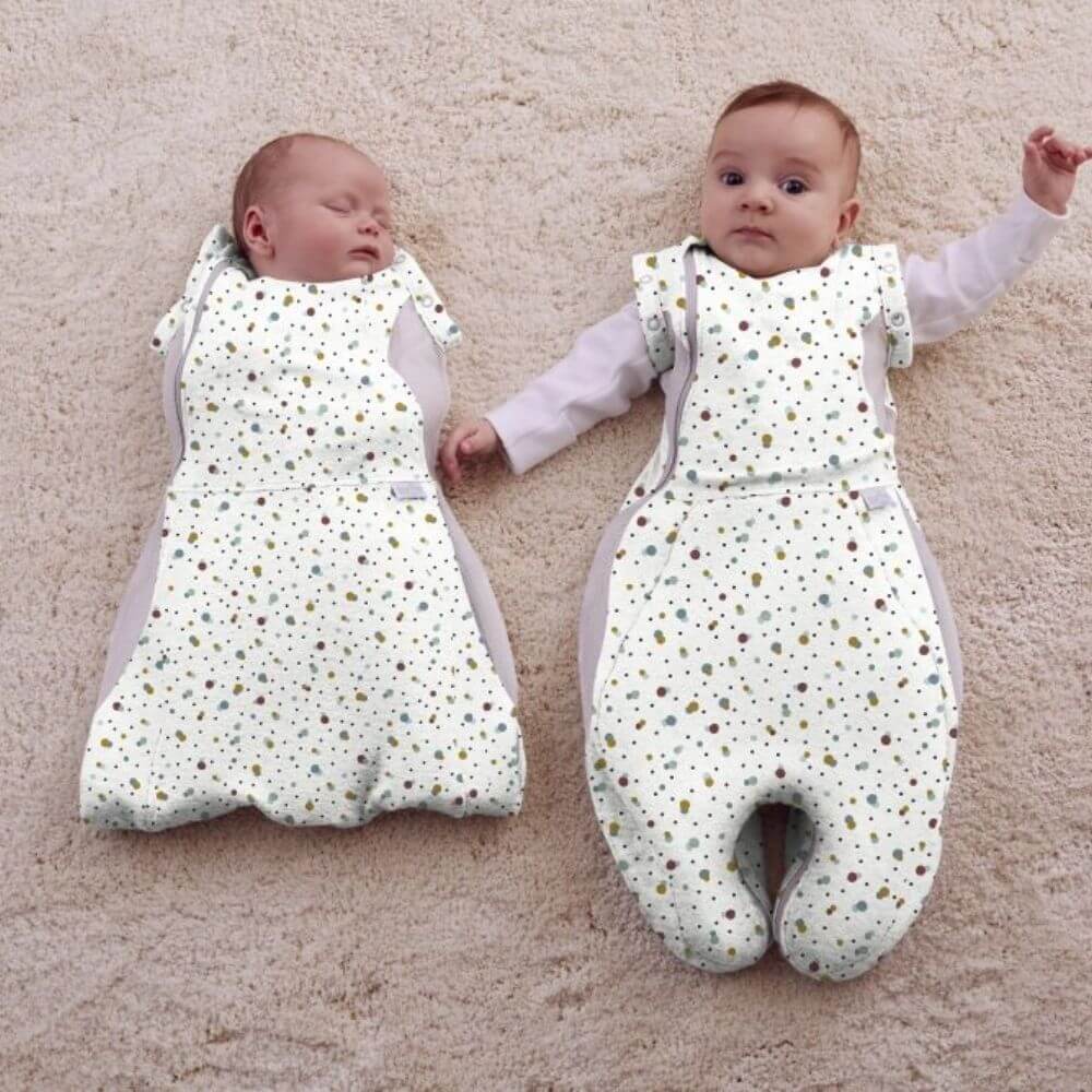 Two babies side by side in adjustments of the Purflo Swaddle to Sleep Bag 0.5 Tog, Scandi Spot design. Adjustable fit and breathable for safe sleep.