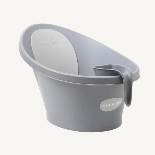 A grey rinsing jug hooked onto the rim of a baby bath, showing compact storage within easy reach during bath time.