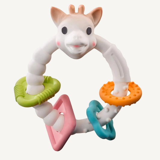 A giraffe-shaped natural rubber teething ring with a flexible white body and multiple textured rings in green, orange, pink, and blue attached around the circular handle.