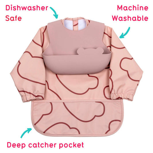A long-sleeve baby bib with a cloud pattern in dusty pink and dark red, featuring a solid pink bib insert, shown on a white background with text callouts indicating dishwasher safe, machine washable, and deep catcher pocket features.