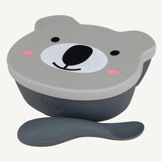 A silicone suction bowl with a bear-shaped lid and matching spoon, shown from a slightly angled top view with the spoon placed in front.