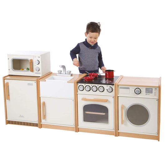 Tidlo Wooden Play Kitchen collection shown together in use, featuring fridge, microwave, sink, cooker and washing machine units, with a child pretending to cook using red pans.