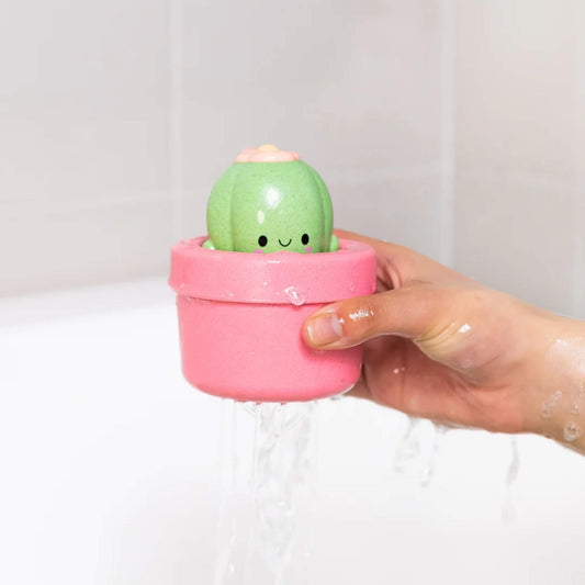 A hand lifting the cactus toy out of the bath with water draining through the bottom.