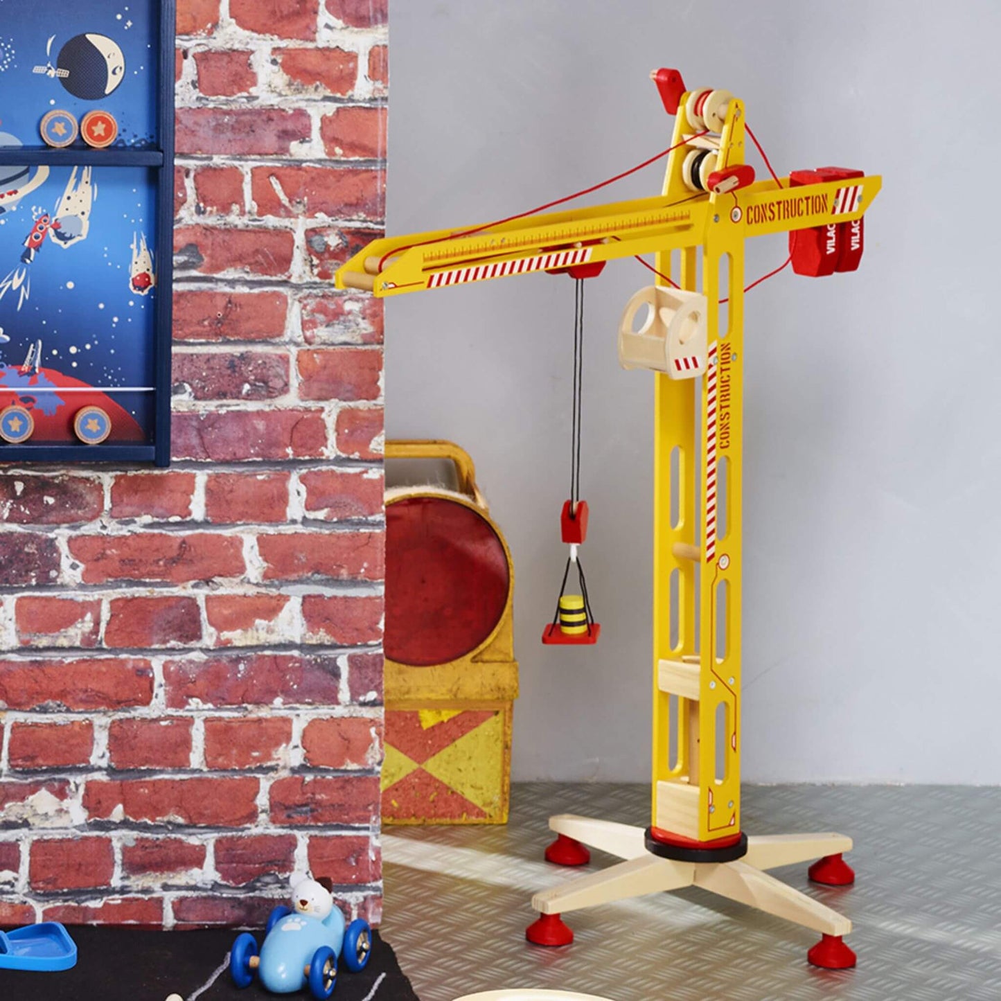 Large yellow wooden crane set against a fun brick and space-themed background, perfect for imaginative construction play.