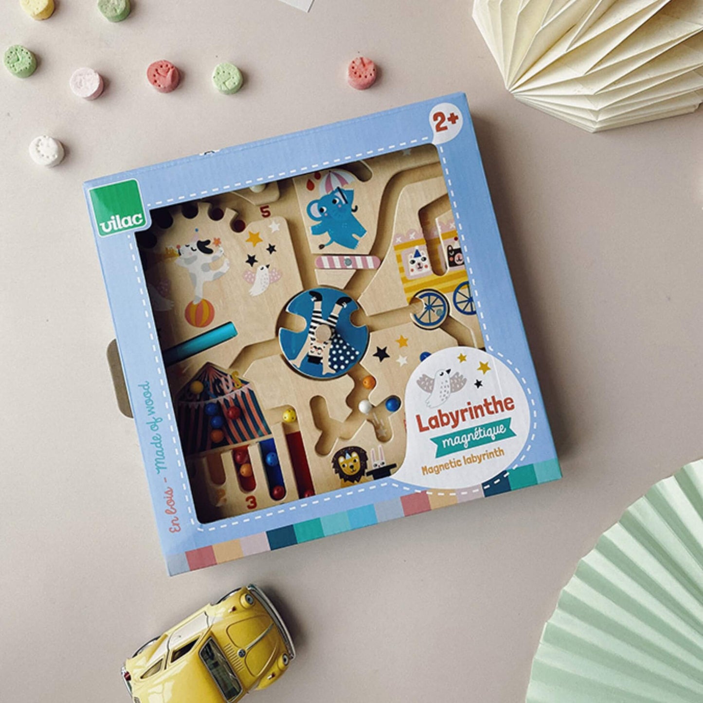 Vilac circus magnetic maze shown in its retail packaging, placed on a table with sweets and a toy car, highlighting the product inside the display box.